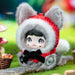 Toy figure with a red and gray outfit, black bow tie, and paw print on a grassy background.