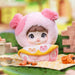 Toy figure in a pink outfit with bear ears on a picnic blanket