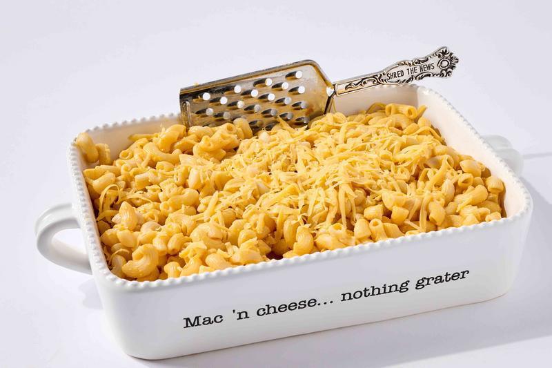 Macaroni and cheese in a dish with a serving spoon on a white background