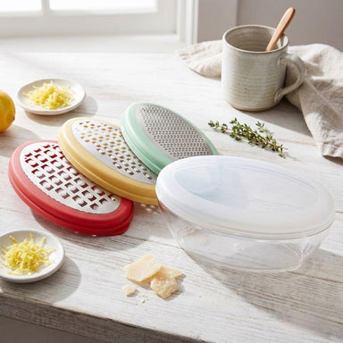 Colorful kitchen sieves on a wooden surface with a cup and lemon in the background.