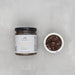 Jar of peach bourbon caramel sauce with a small bowl of the sauce on a light gray background