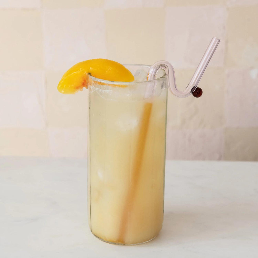 Glass of iced tea with a straw and orange slice on a light background
