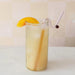 Glass of iced tea with a straw and orange slice on a light background