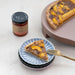 Slice of peach tart on a blue plate with a jar of peach jam in the background.