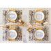 Elegant table setting with gold chargers, plates, and decorative elements on a marble surface.