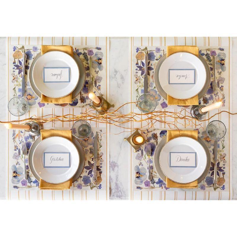 Elegant table setting with gold chargers, plates, and decorative elements on a marble surface.