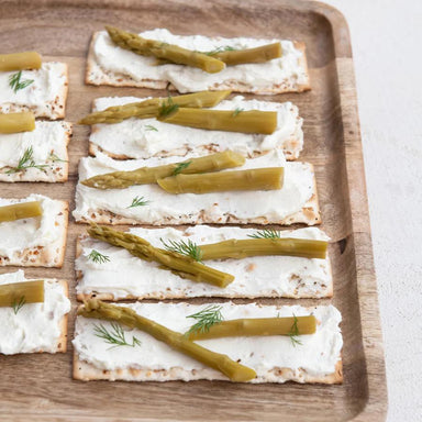  crackers with cream cheese and asparagus on a wooden tray