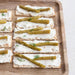  crackers with cream cheese and asparagus on a wooden tray
