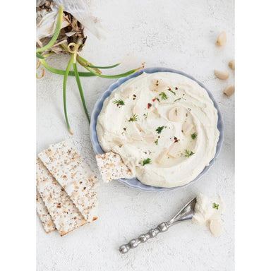 Bowl of white dip with crackers on a light surface