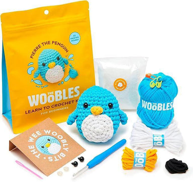 Crochet kit with blue penguin toy, yarn, and tools on a white background
