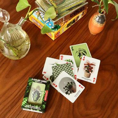Playing cards with plant designs on a wooden table with card boxes in the background