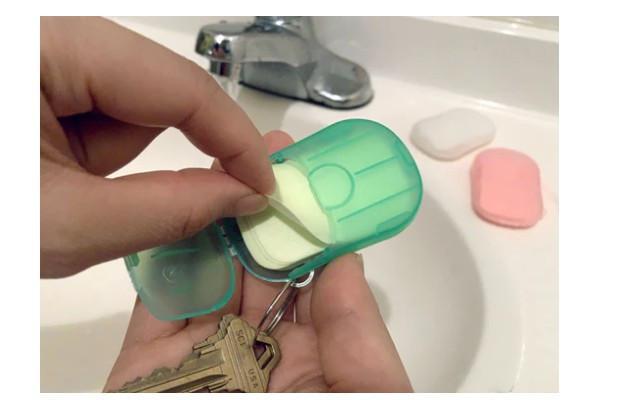 Hand holding a small green container with soap next to a sink.