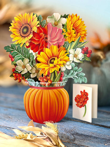 Bouquet of flowers in a pumpkin vase on a wooden surface with a blurred background