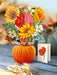 Bouquet of flowers in a pumpkin vase on a wooden surface with a blurred background