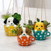 Three hanging planters shaped like dogs in polka dot mugs on a wooden surface.