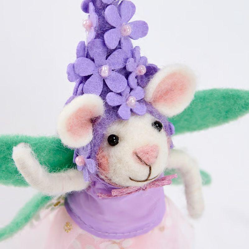 Stuffed mouse toy with a purple outfit and flower hat on a white background