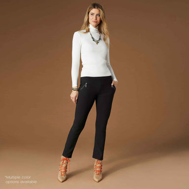 Woman wearing a white turtleneck and black pants against a brown background