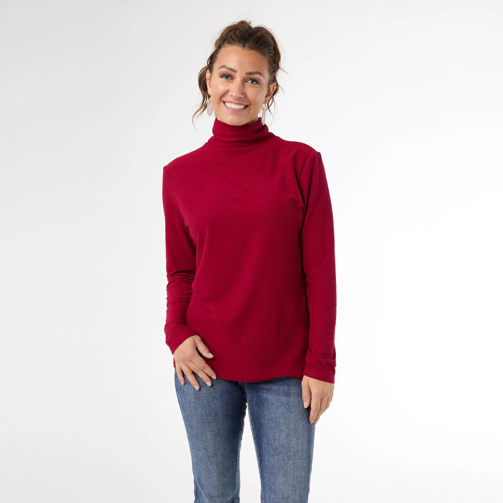 Woman wearing a red turtleneck sweater and blue jeans on a white background
