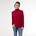 Woman wearing a red turtleneck sweater and blue jeans on a white background