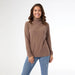 Woman wearing a brown turtleneck sweater and blue jeans on a white background