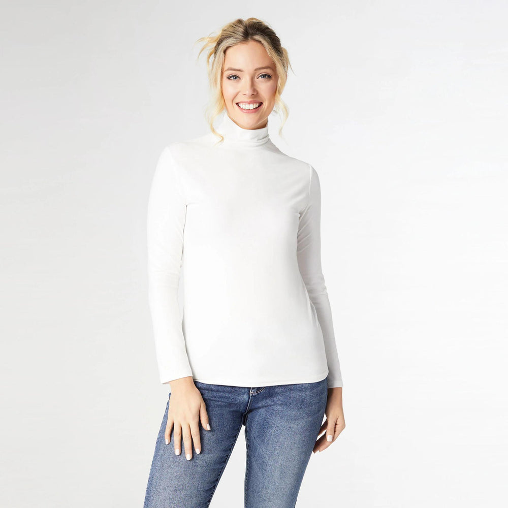 Woman wearing a white turtleneck and blue jeans on a plain background