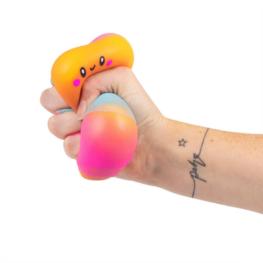 Hand holding a gradient stress ball with a cartoon face on a white background