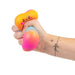 Hand holding a gradient stress ball with a cartoon face on a white background