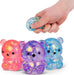 Colorful glittery bear-shaped fidget toys with a hand squeezing one of them.