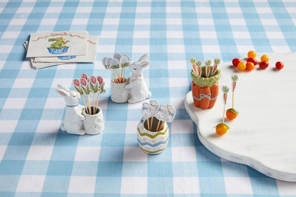 Decorative items on a checkered tablecloth including rabbit-shaped planters and carrot-shaped pots.