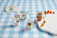 Decorative items on a checkered tablecloth including rabbit-shaped planters and carrot-shaped pots.