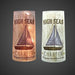 Two cylindrical candles with sailboat design and 'High Seas Charter' text on a dark background