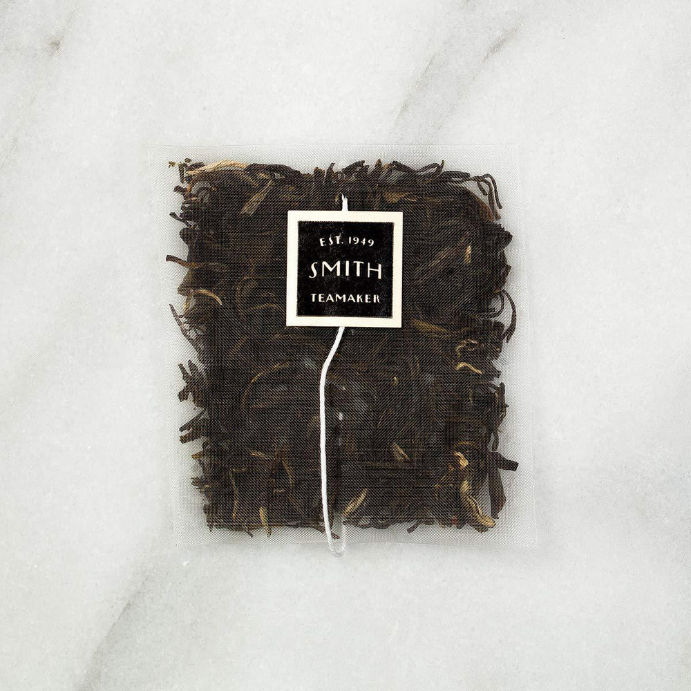 Tea bag with a label on a white marble surface