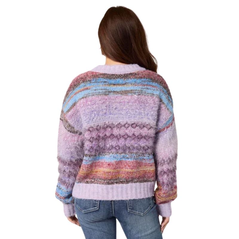 A woman viewed from behind wearing a fuzzy knit sweater with horizontal multicolor stripes in lavender, pink, blue, and brown, paired with blue jeans against a plain white background.