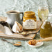 Stonewall Kitchen Maine Maple Champagne Mustard on a wooden tray with coffee, garlic, and honey.