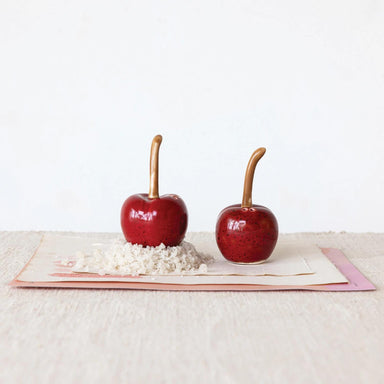 Two red candy apples on a white surface with a white background
