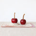 Two red candy apples on a white surface with a white background