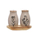 Two ceramic salt and pepper shakers with floral designs on a wooden tray against a white background.