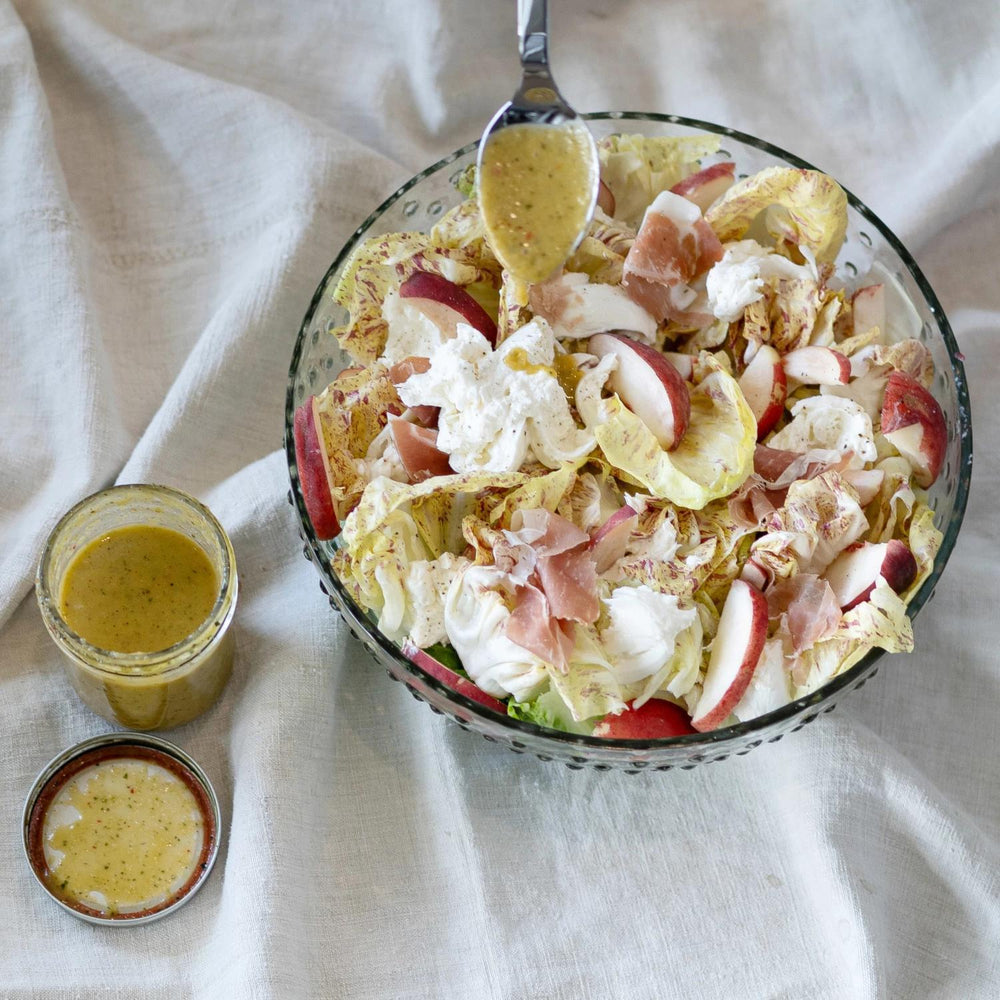 Salad with apples and croutons in a glass bowl on a white cloth background