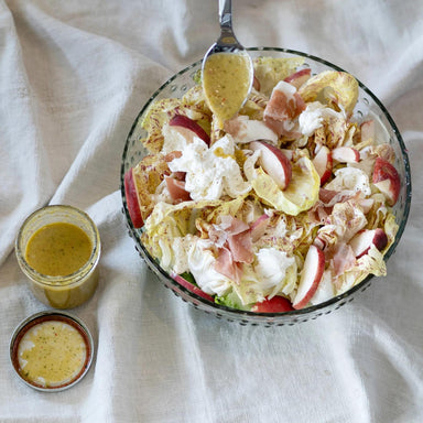 Salad with apples and croutons in a glass bowl on a white cloth background