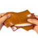 Hands holding a brown silicone bag with a white interior on a white background