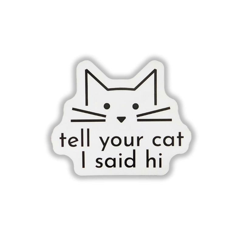 A die-cut white sticker featuring a minimalist black line drawing of a cat's face above the text 'tell your cat I said hi' in black lowercase letters, shown on a plain white background.