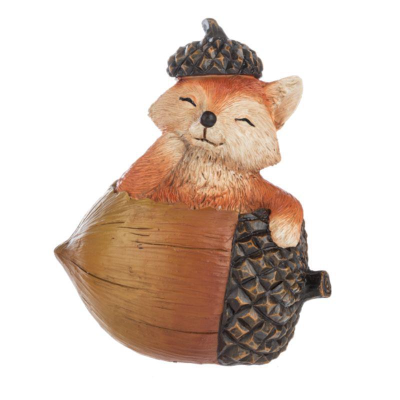 Fox figurine inside an acorn with a pinecone on a white background