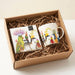 Two mugs with bird designs in a cardboard box with straw padding.