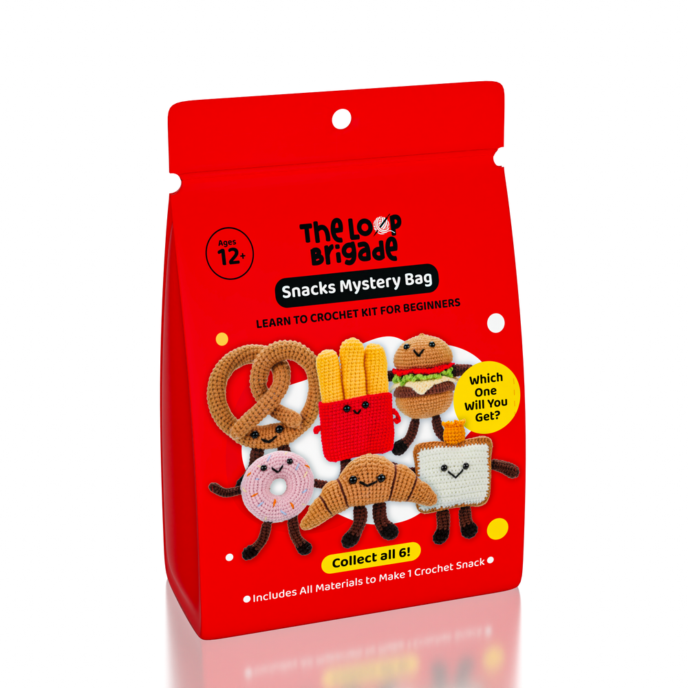 Red packaging of 'The Lolo Brigade' snacks mystery bag with crochet snack models on a white background