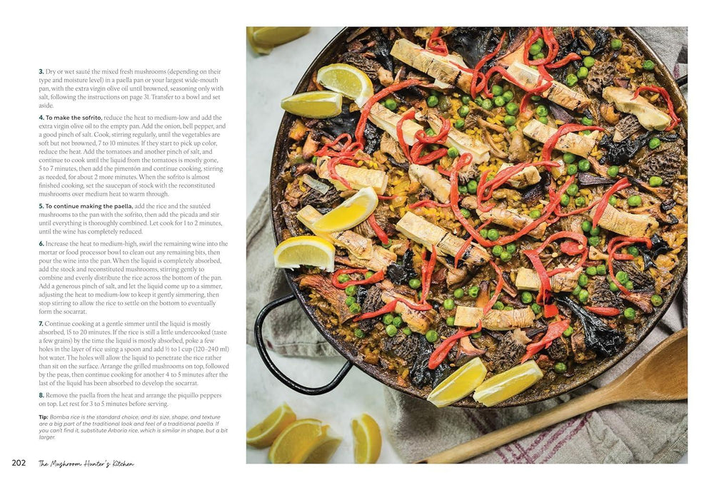 Paella dish with vegetables and lemon wedges on a white surface
