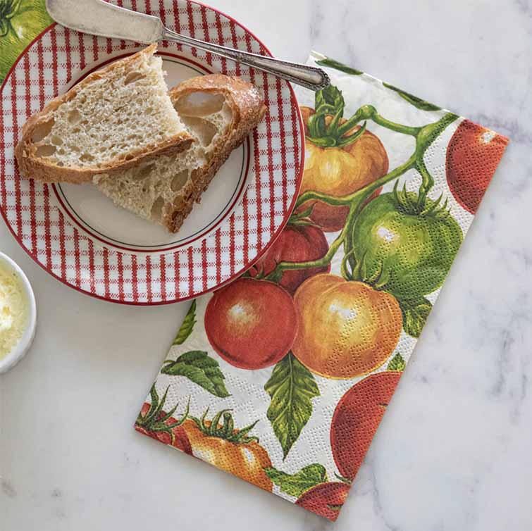 Napkin with tomato pattern next to a plate of bread and butter