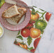 Napkin with tomato pattern next to a plate of bread and butter