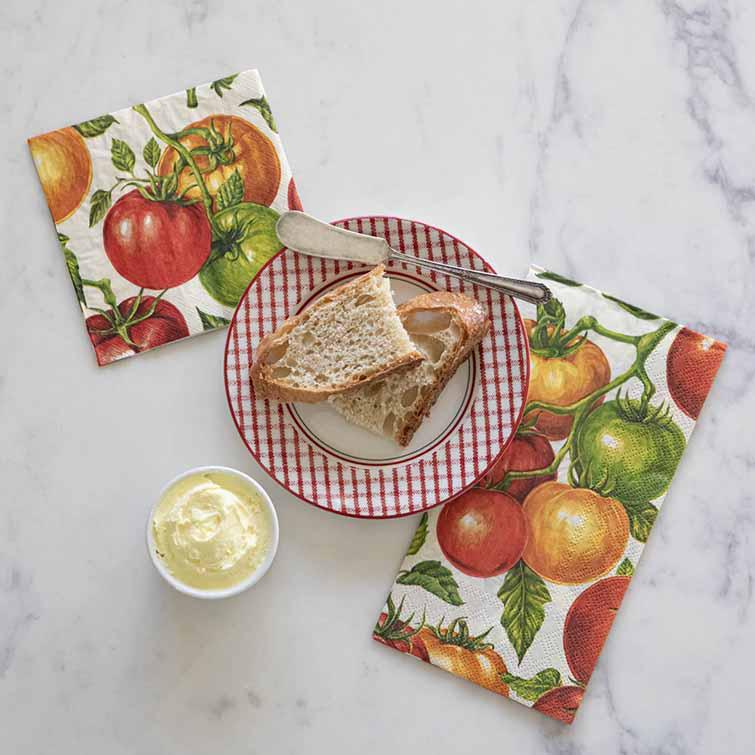 Napkins with tomato design, bread, butter, and knife on a marble surface