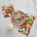 Napkins with tomato design, bread, butter, and knife on a marble surface