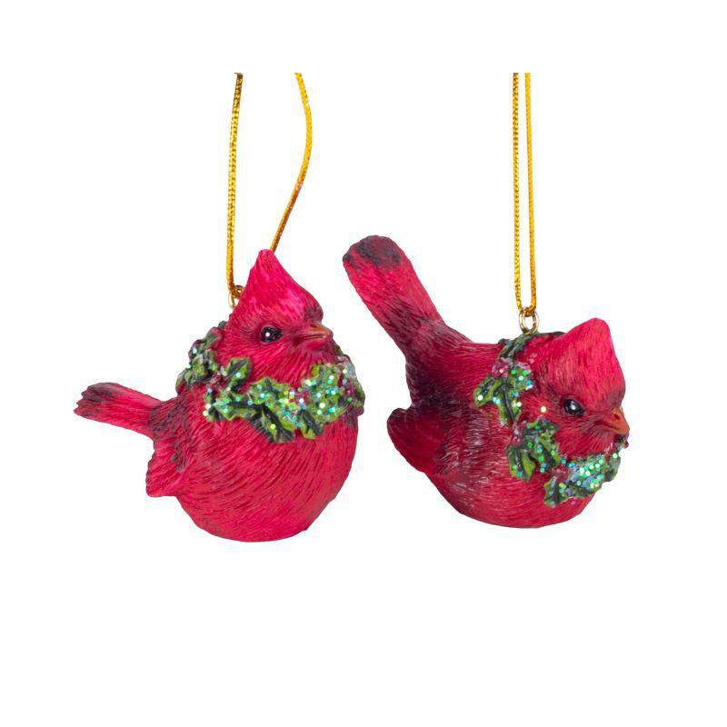 Two red cardinal bird ornaments with green wreaths on a white background